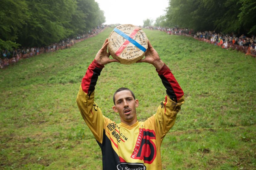 Chris Anderson, 30 anos, quebrou o recorde histórico de maior número de queijos ganhos na desafiadora Corrida de Queijos Rolantes em Cooper's Hill, na Inglaterra • Aaron Chown/PA Images via Getty Images